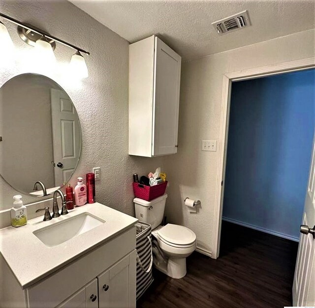 bathroom with toilet, vanity, a textured ceiling, and hardwood / wood-style flooring