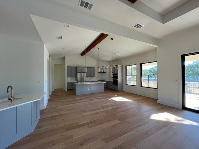 kitchen featuring a center island, hanging light fixtures, vaulted ceiling with beams, stainless steel fridge, and light wood-type flooring