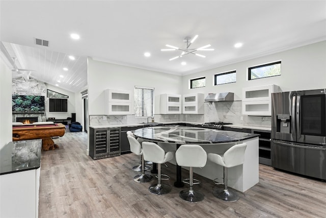 5110 Sioux Ln, Austin, TX 78734 - kitchen with stainless steel fridge, beverage cooler, a breakfast bar, wall chimney range hood, and a center island