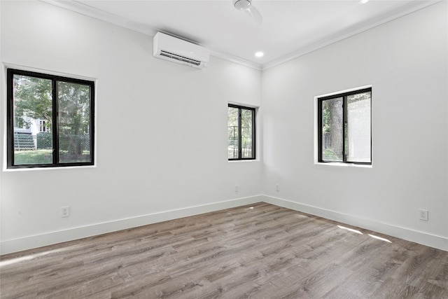 unfurnished room with a wall mounted AC, light hardwood / wood-style floors, a healthy amount of sunlight, and ornamental molding