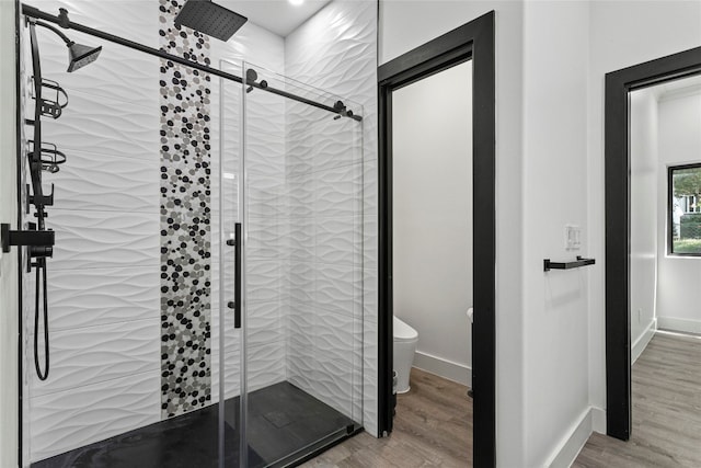 bathroom featuring hardwood / wood-style flooring, toilet, and a shower with door