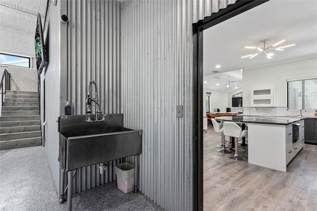 misc room featuring a chandelier, light hardwood / wood-style floors, crown molding, and sink