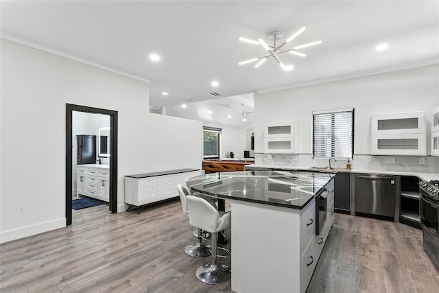 kitchen featuring tasteful backsplash, stainless steel dishwasher, a kitchen island, white cabinetry, and a breakfast bar area