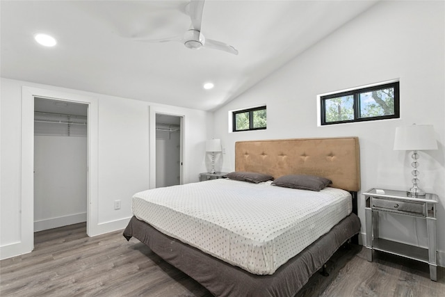 bedroom featuring a walk in closet, hardwood / wood-style flooring, vaulted ceiling, and ceiling fan