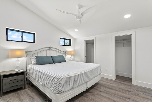 bedroom featuring ceiling fan, hardwood / wood-style floors, lofted ceiling, a walk in closet, and a closet