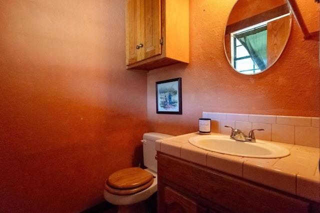 bathroom featuring vanity, toilet, and backsplash