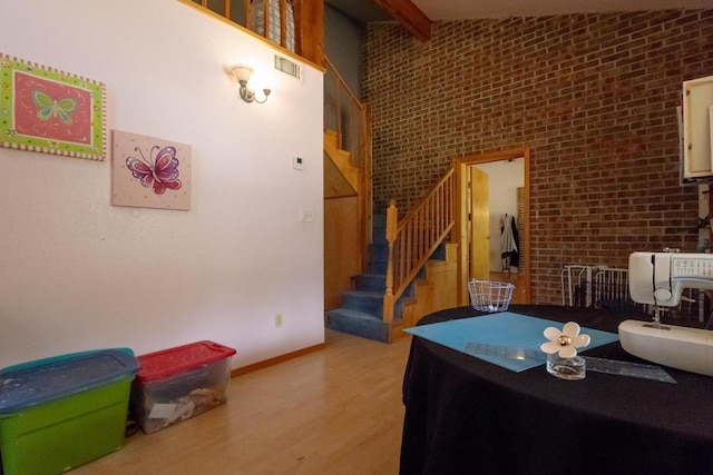 dining area featuring lofted ceiling with beams, light hardwood / wood-style floors, and brick wall