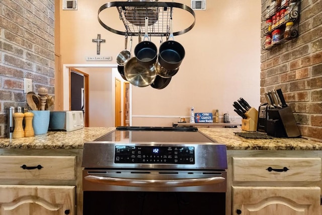 kitchen with stove, light stone counters, and light brown cabinetry