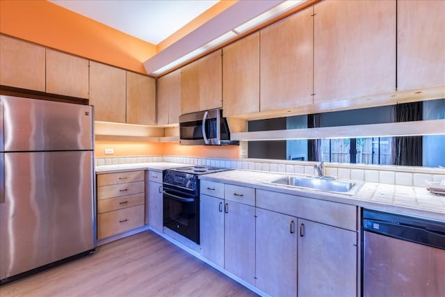 kitchen with appliances with stainless steel finishes, light wood-type flooring, light brown cabinets, and sink