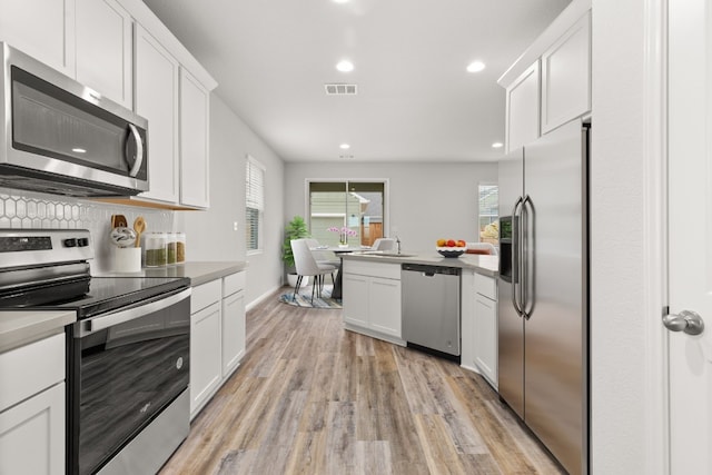 kitchen with white cabinetry, sink, stainless steel appliances, and light hardwood / wood-style floors