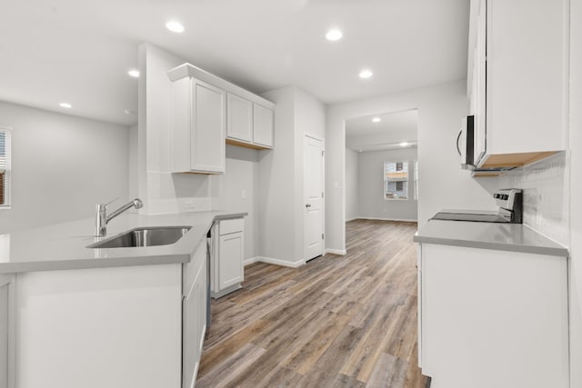 kitchen with sink, white cabinets, range, kitchen peninsula, and light wood-type flooring