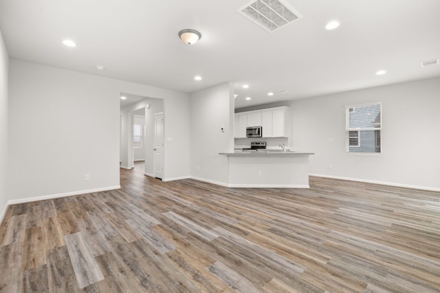 unfurnished living room with a healthy amount of sunlight and light hardwood / wood-style floors