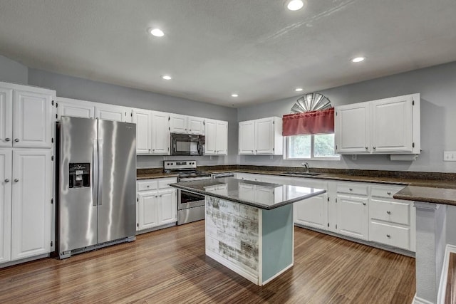 kitchen with sink, light wood-type flooring, appliances with stainless steel finishes, a kitchen island, and white cabinets