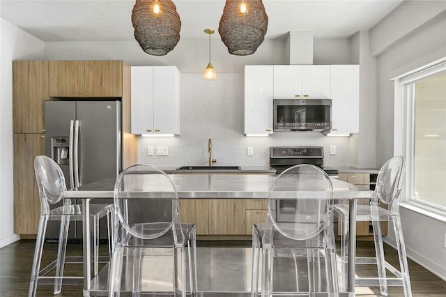 kitchen featuring white cabinetry, decorative backsplash, stainless steel appliances, and sink