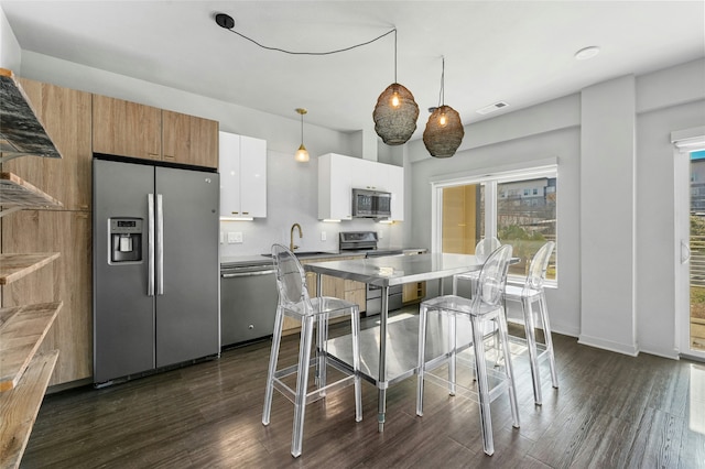 kitchen featuring sink, hanging light fixtures, appliances with stainless steel finishes, white cabinets, and dark hardwood / wood-style flooring