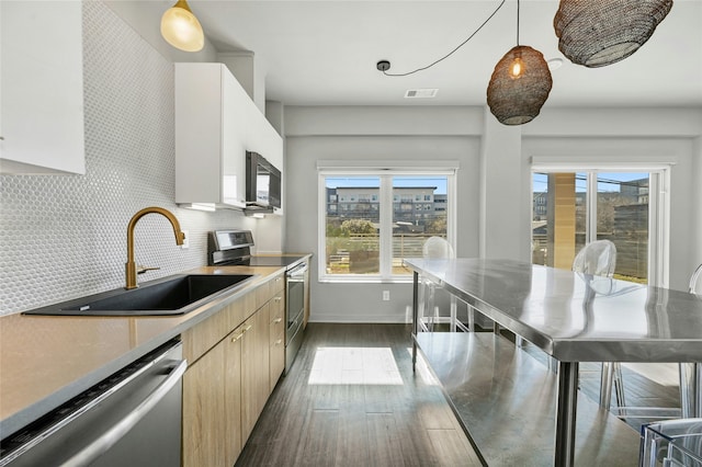 kitchen featuring appliances with stainless steel finishes, decorative light fixtures, sink, backsplash, and plenty of natural light