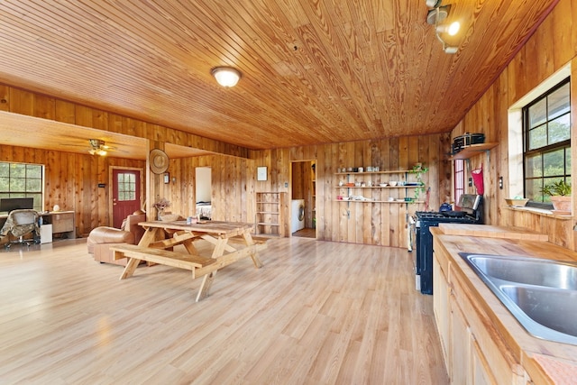 kitchen featuring wooden walls, range with gas cooktop, light wood-type flooring, and wood ceiling