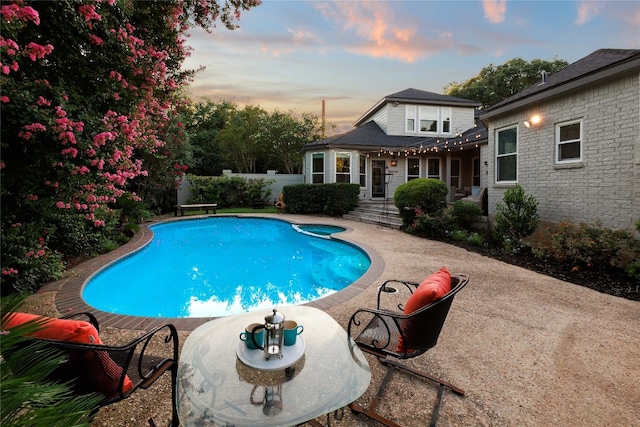 pool at dusk featuring a patio