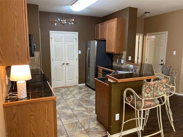 kitchen with light tile patterned flooring, a breakfast bar area, tasteful backsplash, kitchen peninsula, and sink