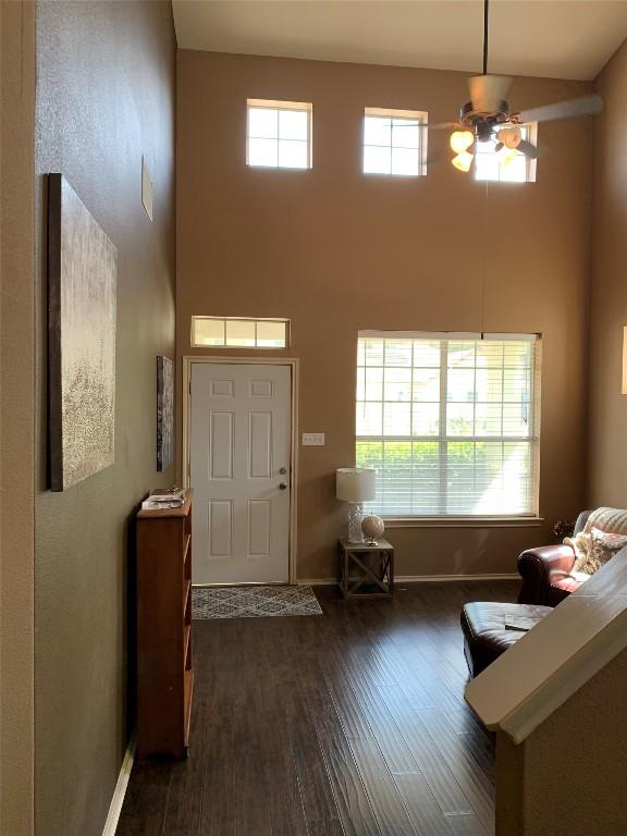 entryway with dark hardwood / wood-style floors, ceiling fan, and a towering ceiling