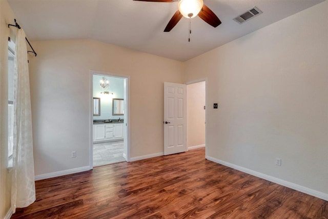 unfurnished bedroom featuring ceiling fan with notable chandelier, ensuite bathroom, dark hardwood / wood-style floors, and lofted ceiling