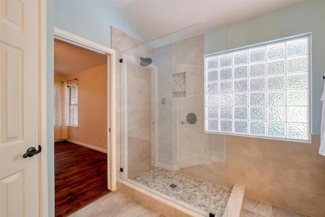 bathroom featuring a tile shower, tile patterned floors, and vaulted ceiling