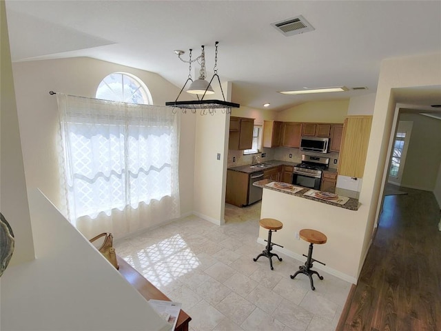 kitchen featuring hanging light fixtures, lofted ceiling, sink, and appliances with stainless steel finishes