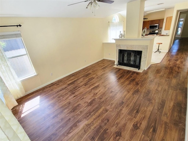 unfurnished living room with a high end fireplace, a wealth of natural light, dark wood-type flooring, and ceiling fan