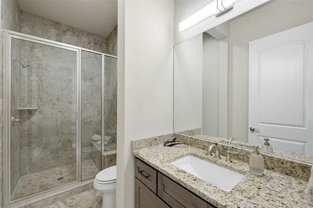 bathroom featuring a shower with door, vanity, and toilet