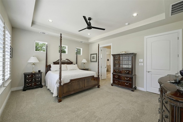 carpeted bedroom featuring multiple windows, a raised ceiling, and ceiling fan