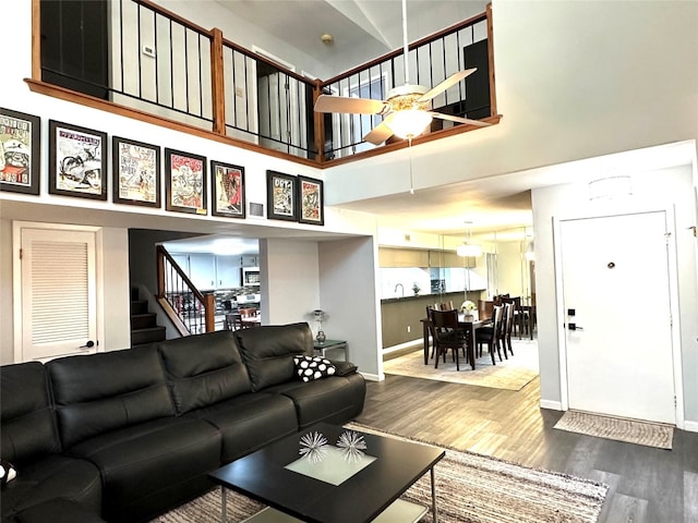 living room featuring ceiling fan, hardwood / wood-style floors, and a high ceiling