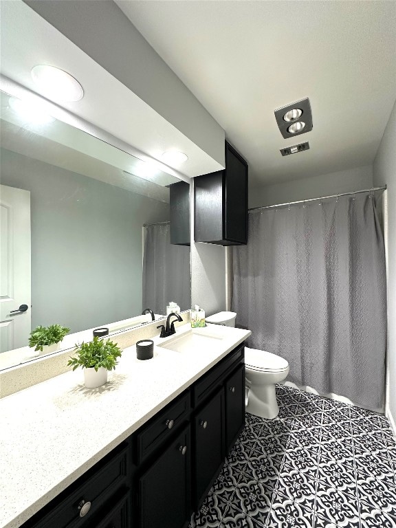 bathroom with curtained shower, vanity, toilet, and tile patterned floors