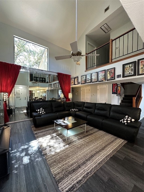 living room featuring dark hardwood / wood-style floors, a towering ceiling, and ceiling fan