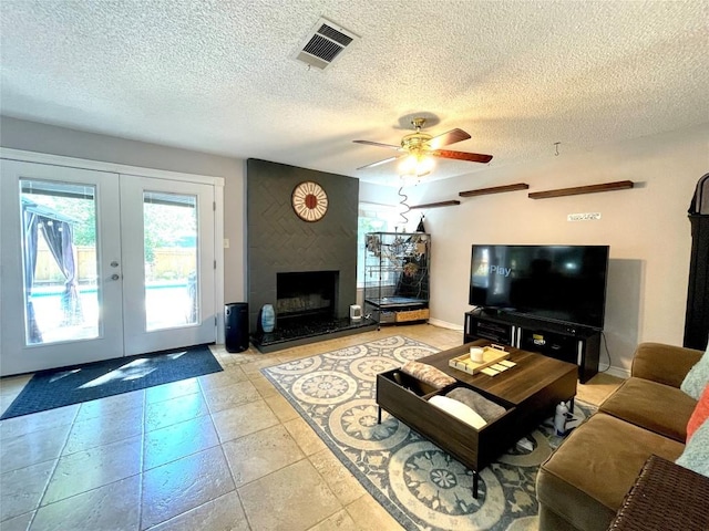 living room featuring ceiling fan, a textured ceiling, a high end fireplace, and french doors