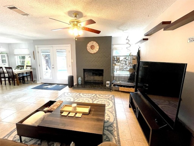 13242 Kerrville Folkway, Austin, TX 78729 - living area featuring a textured ceiling, ceiling fan, french doors, a fireplace, and light tile patterned floors