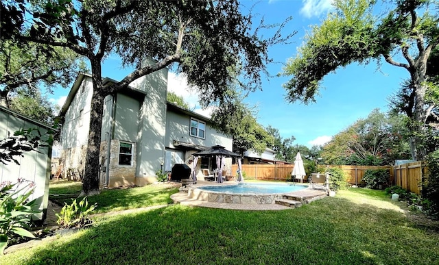 rear view of property featuring a gazebo, a yard, and a fenced in pool