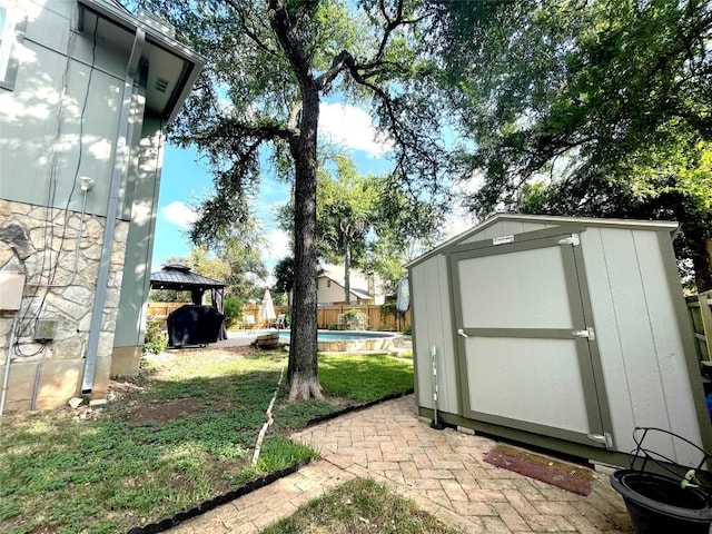 view of yard featuring a fenced in pool, a gazebo, and a storage shed