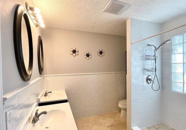 13242 Kerrville Folkway, Austin, TX 78729 - full bath featuring a textured ceiling, tile walls, toilet, a tile shower, and double vanity