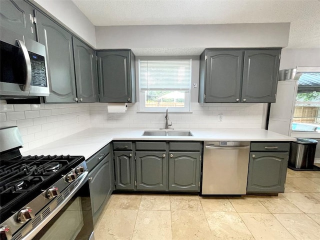 kitchen featuring sink, gray cabinets, appliances with stainless steel finishes, tasteful backsplash, and a textured ceiling