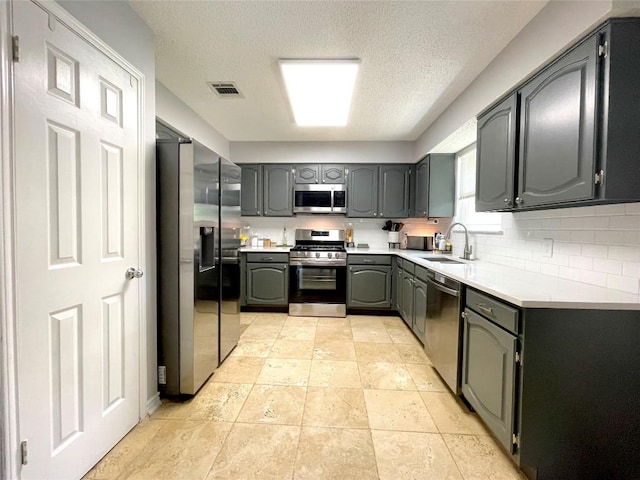 13242 Kerrville Folkway, Austin, TX 78729 - kitchen featuring stainless steel appliances, a sink, gray cabinetry, a textured ceiling, and light countertops