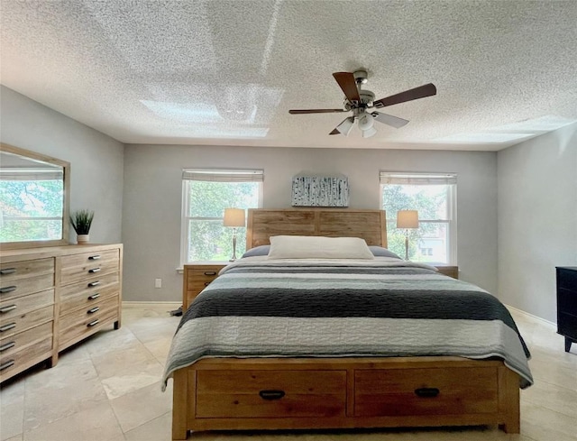 bedroom featuring multiple windows, a textured ceiling, and ceiling fan