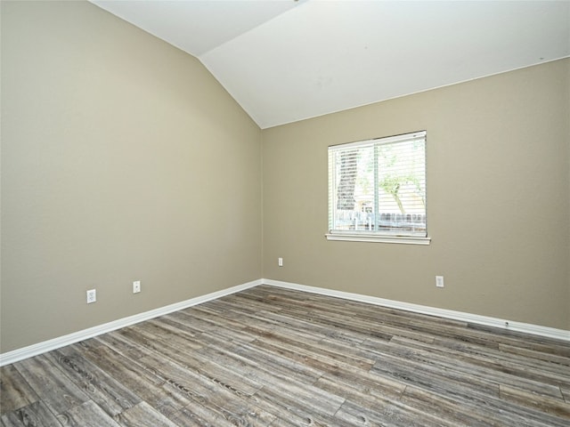 spare room featuring wood-type flooring and lofted ceiling