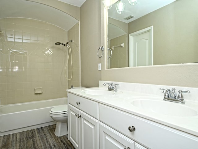 full bathroom featuring hardwood / wood-style flooring, tiled shower / bath combo, toilet, and vanity