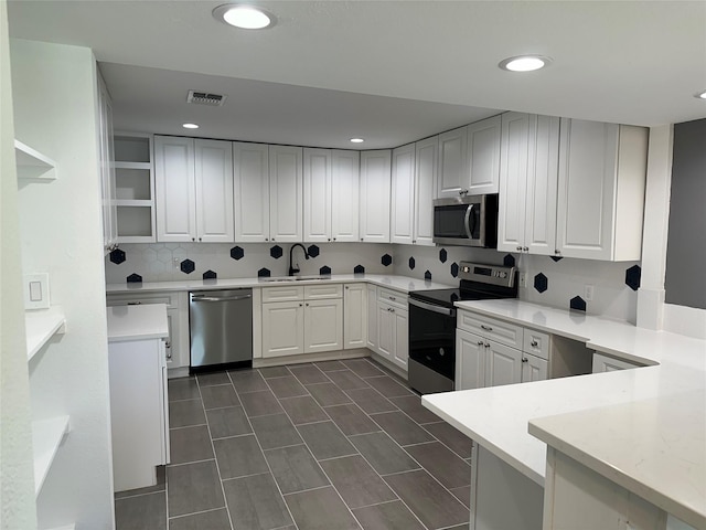 kitchen featuring kitchen peninsula, stainless steel appliances, white cabinetry, and sink