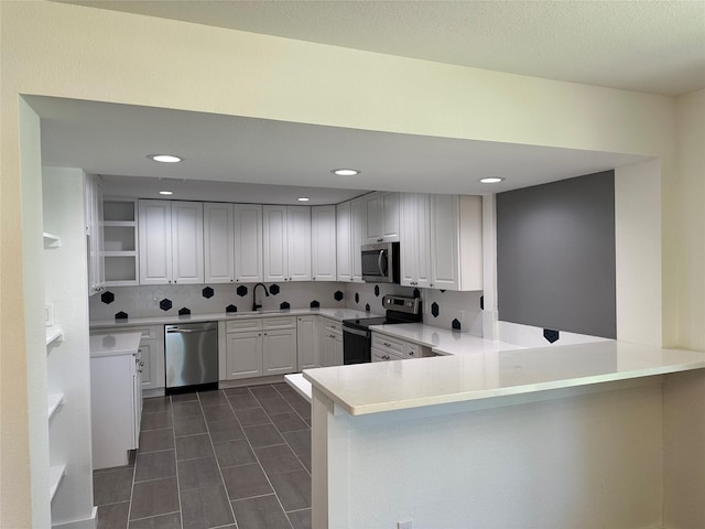 kitchen with white cabinets, kitchen peninsula, appliances with stainless steel finishes, and sink