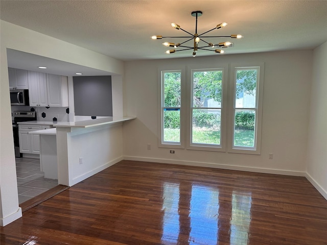 kitchen with an inviting chandelier, white cabinetry, kitchen peninsula, electric range, and dark wood-type flooring