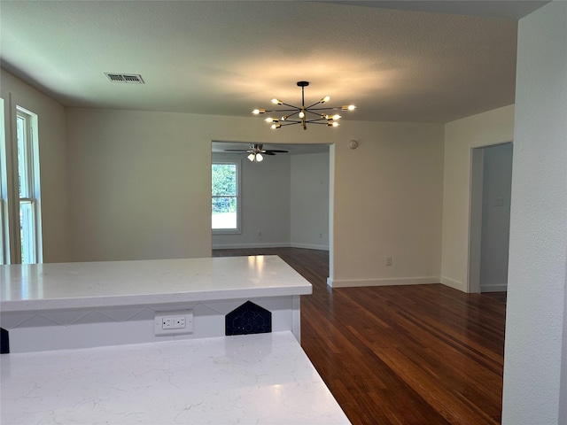 kitchen with dark hardwood / wood-style floors, ceiling fan with notable chandelier, light stone counters, and a textured ceiling