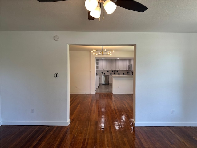 unfurnished room featuring ceiling fan with notable chandelier and dark hardwood / wood-style floors