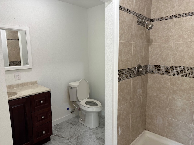 bathroom featuring toilet, a tile shower, and vanity