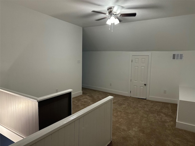 hall featuring lofted ceiling and dark colored carpet